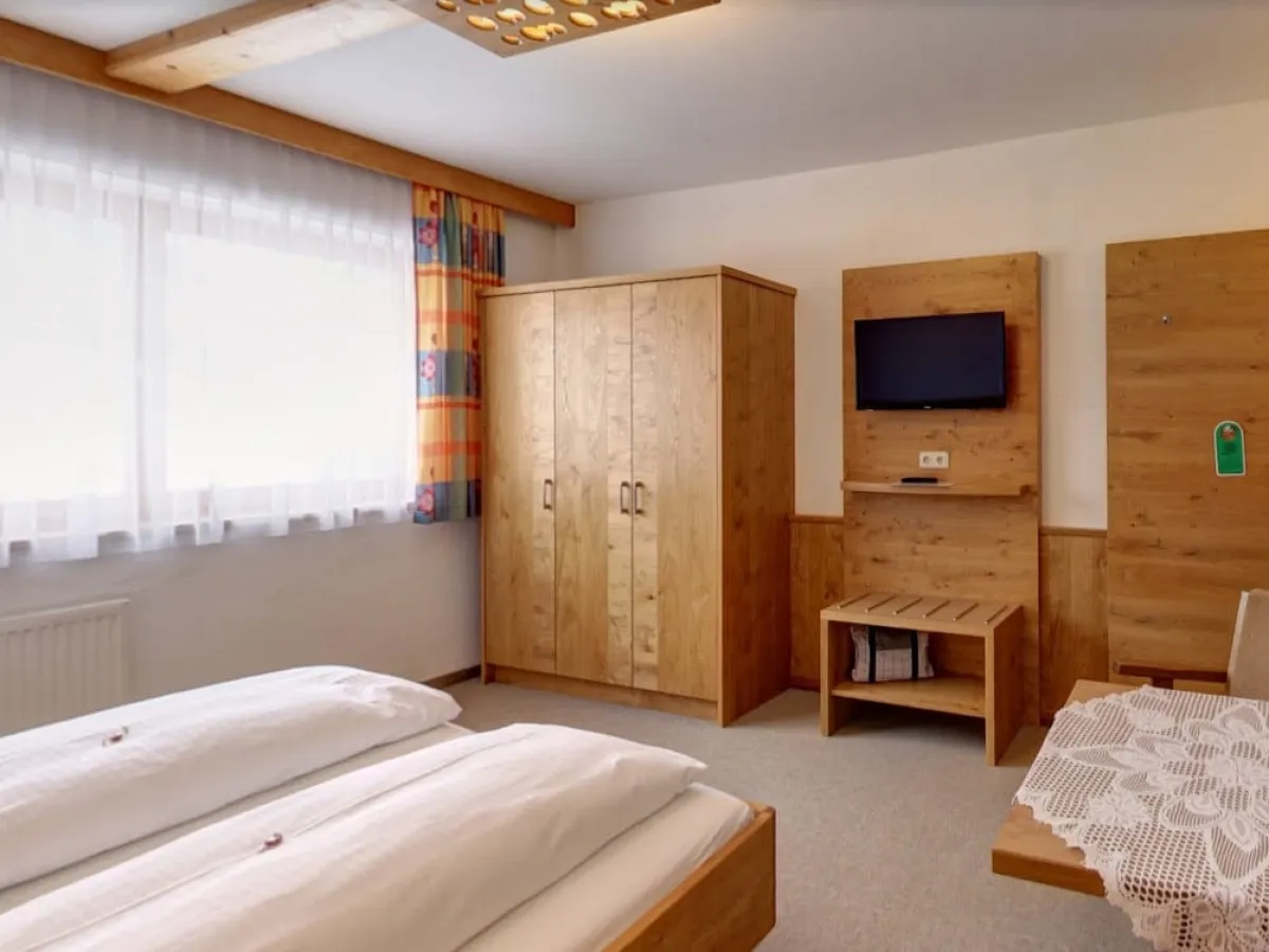 Helles, modernes Zimmer mit zwei Betten, Holzschränken und TV.