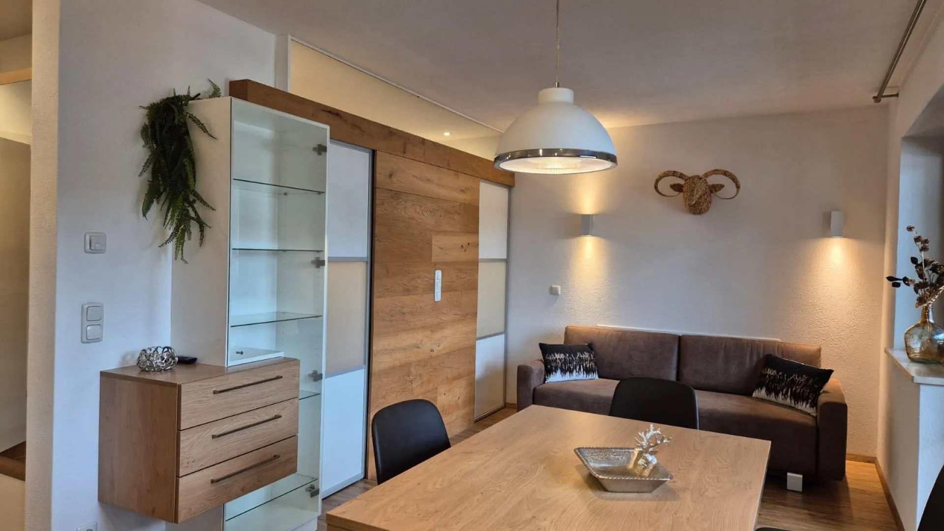 modernes Wohnzimmer mit Holzregalen, Couch und Esstisch