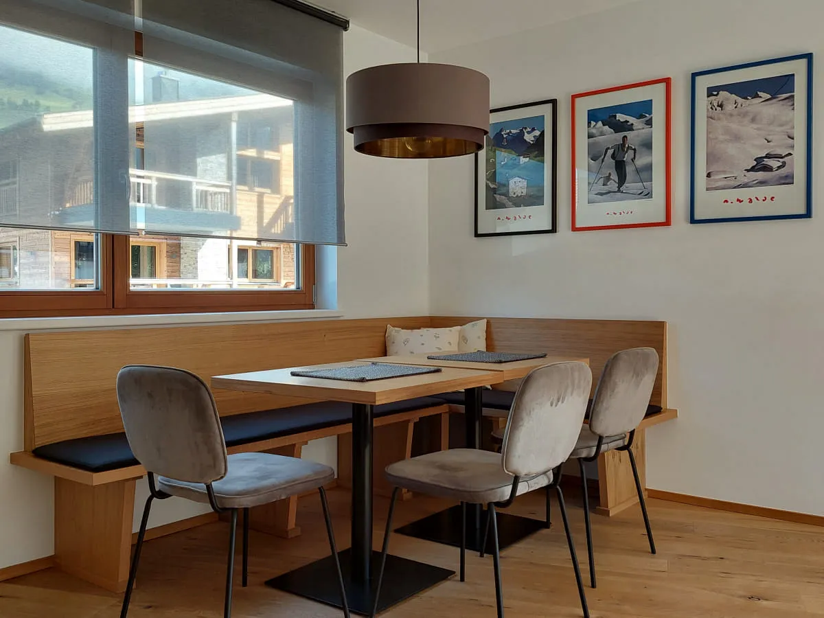 Essbereich mit Tisch, Stühlen und rahmenlosen Fenstern, Bildern an der Wand